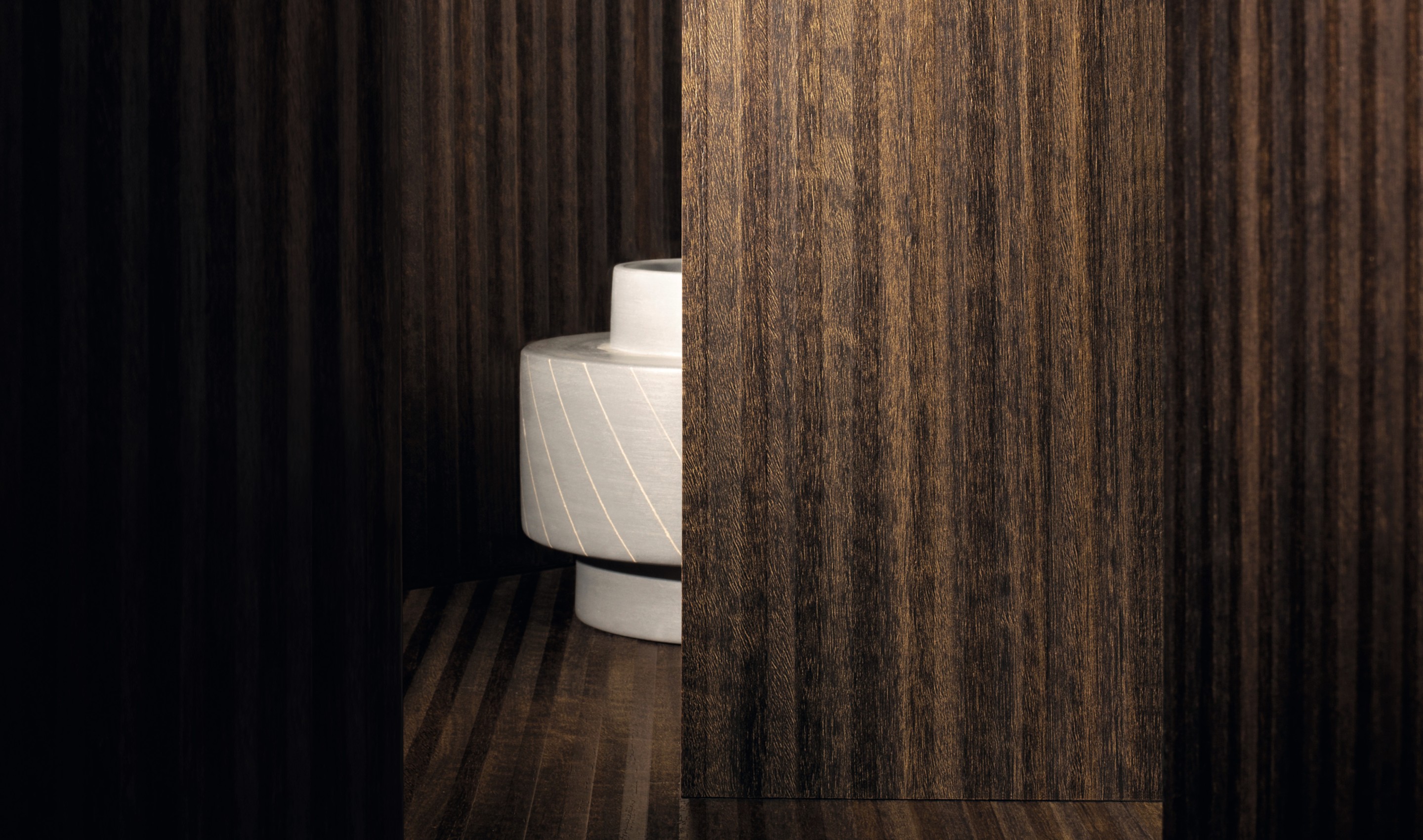 Ein kurzen Flur mit dem Holzdekor Querica S203, sandfarbener Wand und einem Eichen-Ast-Schatten. Links steht Text. 